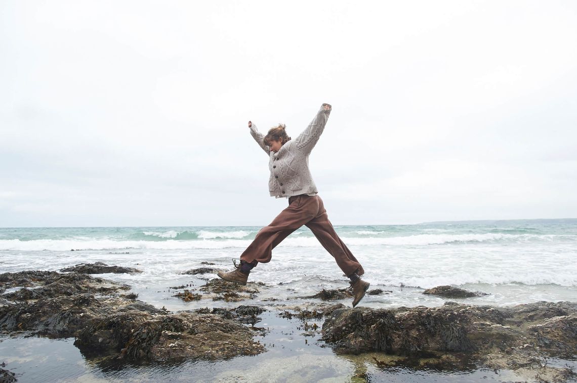woman jumping over rocks